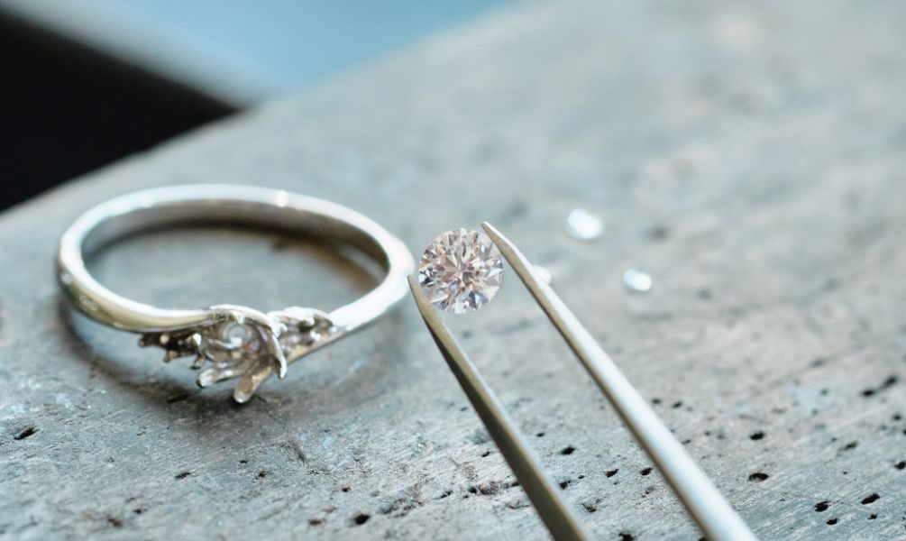 ピンセットでつままれたダイヤモンドと婚約指輪